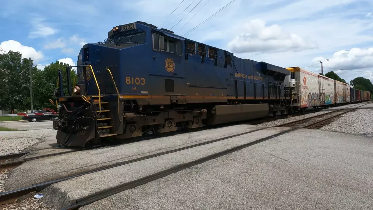Norfolk and Western 8103 freight train crossing road with graffiti boxcars behind