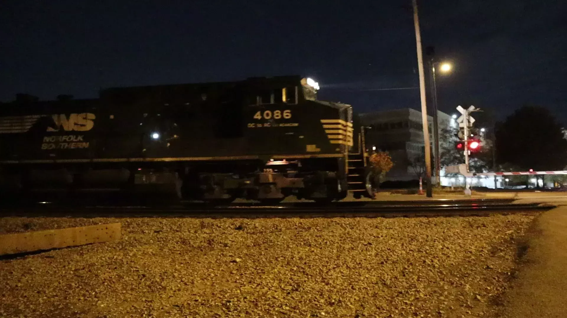 Norfolk Southern 4086 passing night crossing with red signal lights and lowered gate