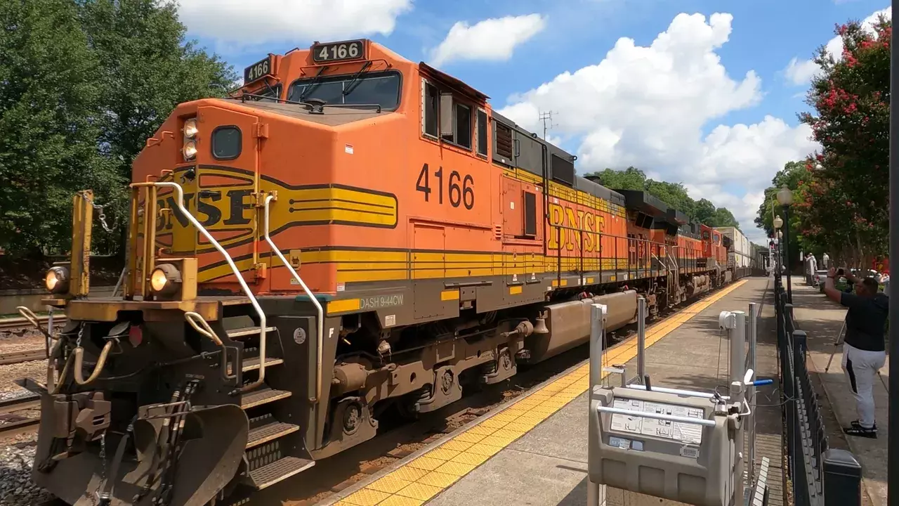 BNSF locomotive 4166 at station platform with railfan taking photo nearby