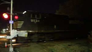 Freight train passing railroad crossing at night with red signal lights